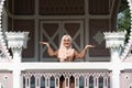 Young diverse woman raising hands in the air wearing hijab and smiling outdoors