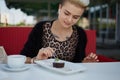 Young diverse woman with short hair eating a sweet dessert for lunch in a outdoor cafe. Portrait of a tattooed young tom boy Royalty Free Stock Photo