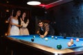 Young diversity group of people playing pool together with smile, enjoyment and fun. Young people spend time in billiards room. Royalty Free Stock Photo
