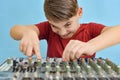 A young DJ is adjusting the equalizer on a music mixing console