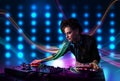 Young Dj girl mixing records with colorful lights