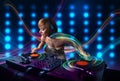 Young Dj girl mixing records with colorful lights