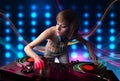 Young Dj girl mixing records with colorful lights