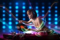 Young Dj girl mixing records with colorful lights