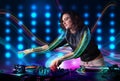 Young Dj girl mixing records with colorful lights