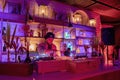 Young DJ playing music on sound mixer at illuminated decorated pub in resort