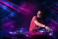 Young DJ playing on turntables with color light effects Royalty Free Stock Photo