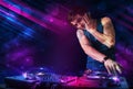 Young DJ playing on turntables with color light effects Royalty Free Stock Photo