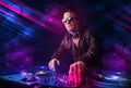 Young DJ playing on turntables with color light effects Royalty Free Stock Photo