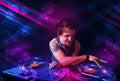 Young DJ playing on turntables with color light effects Royalty Free Stock Photo