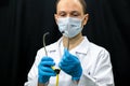 A young doctor in blue gloves and a stethoscope around his neck on a black background. Portrait of a doctor with medical Royalty Free Stock Photo