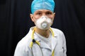 A young doctor in blue gloves and a stethoscope around his neck on a black background. Portrait of a doctor with medical Royalty Free Stock Photo