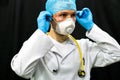 A young doctor in blue gloves and a stethoscope around his neck on a black background. Portrait of a doctor with medical Royalty Free Stock Photo