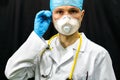 A young doctor in blue gloves and a stethoscope around his neck on a black background. Portrait of a doctor with medical Royalty Free Stock Photo