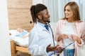 Young doctor with clipboard talking to a smiling woman Royalty Free Stock Photo