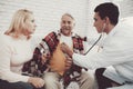 Young Doctor in Coat Visiting Old Couple at Home. Royalty Free Stock Photo