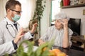 Young doctor consulting and advising senior woman during house call visit Royalty Free Stock Photo