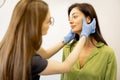 Dermatologist or cosmetologist examining facial skin of woman
