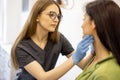 Dermatologist or cosmetologist examining facial skin of woman