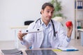 Young male doctor dietician holding apple and pizza box