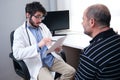 Young doctor health care professional talking with a senior man patient holding a paper and a pen Royalty Free Stock Photo