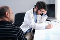 Young doctor health care professional writing a prescription to a senior man patient Royalty Free Stock Photo