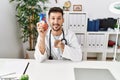 Young doctor holding heart at medical clinic pointing finger to one self smiling happy and proud Royalty Free Stock Photo