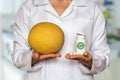 Young doctor holding yellow melon and bottle of pills with vitam Royalty Free Stock Photo
