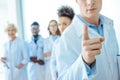 Young doctor in lab coat pointing his finger with group of young doctors in lab coats standing Royalty Free Stock Photo