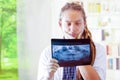 Young doctor with long dread locks posing for camera, holding up x ray image staring at it, clinic in background Royalty Free Stock Photo