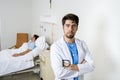 Young doctor looking serious worried corporate portrait at hospital bedroom with sick patient Royalty Free Stock Photo