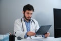 Young doctor looking at a X-ray of a pelvis and spinal column at desk. Royalty Free Stock Photo