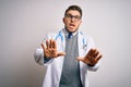 Young doctor man with blue eyes wearing medical coat and stethoscope over isolated background afraid and terrified with fear Royalty Free Stock Photo