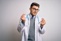 Young doctor man with blue eyes wearing medical coat and stethoscope over isolated background doing money gesture with hands, Royalty Free Stock Photo