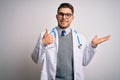 Young doctor man with blue eyes wearing medical coat and stethoscope over isolated background Showing palm hand and doing ok Royalty Free Stock Photo