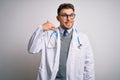 Young doctor man with blue eyes wearing medical coat and stethoscope over isolated background smiling doing phone gesture with Royalty Free Stock Photo