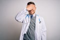 Young doctor man with blue eyes wearing medical coat and stethoscope over isolated background smiling and laughing with hand on Royalty Free Stock Photo