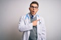 Young doctor man with blue eyes wearing medical coat and stethoscope over isolated background Surprised pointing with finger to Royalty Free Stock Photo