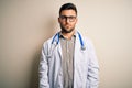 Young doctor man wearing glasses, medical white robe and stethoscope over isolated background depressed and worry for distress, Royalty Free Stock Photo