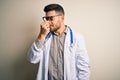 Young doctor man wearing glasses, medical white robe and stethoscope over isolated background tired rubbing nose and eyes feeling Royalty Free Stock Photo