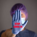 A young doctor in medical uniform with a protective face mask and a gloved hand showing a stop sign - Stop coronavirus, covid-19. Royalty Free Stock Photo