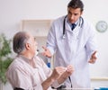 Young male doctor and old patient in antismoking concept