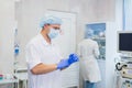 Young doctor during preparation for operation. Assistant of surgeon wearing surgical mask in operation room at the Royalty Free Stock Photo