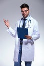 Young doctor presenting with clipboard in hand