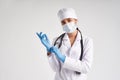 Young doctor putting on surgical gloves over white background Royalty Free Stock Photo