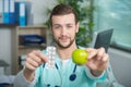 Young doctor showing apple and tablets