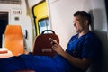 Young doctor sitting with his smartphone in the ambulance car at night Royalty Free Stock Photo