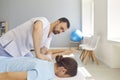 Young doctor specialist curing client`s back and shoulders in modern health center