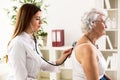 Young doctor with stethoscope exam senior woman