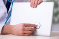 Young male doctor with stethoscope repairing computer Royalty Free Stock Photo